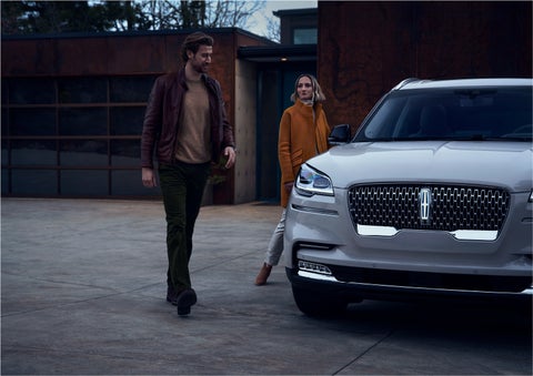 A man and a woman approaching a 2023 Lincoln Aviator® SUV, which illuminates certain lights when they are close | Oliver Lincoln in Plymouth IN