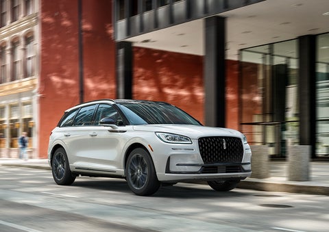 The 2024 Lincoln Corsair® SUV with the Jet Appearance Package and a Pristine White exterior is parked on a city street. | Oliver Lincoln in Plymouth IN